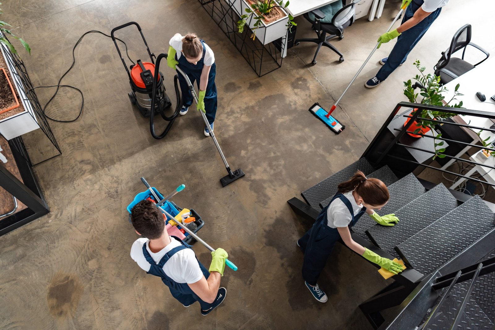 Twee schoonmakers die een woonkamer schoonmaken met een dweil en andere schoonmaakmaterialen.